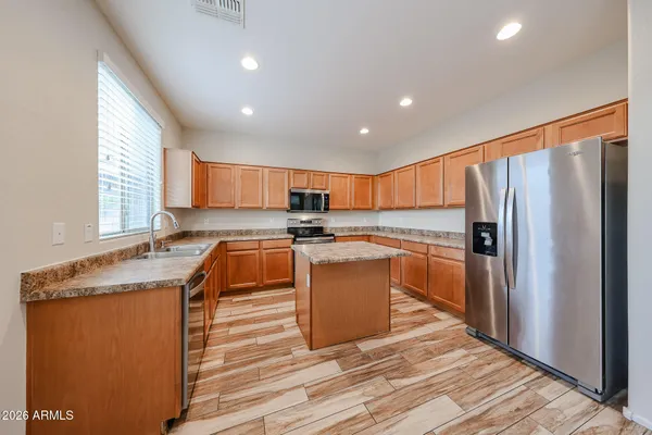 a kitchen with stainless steel appliances granite countertop a refrigerator a sink dishwasher a stove and white countertops with wooden floor