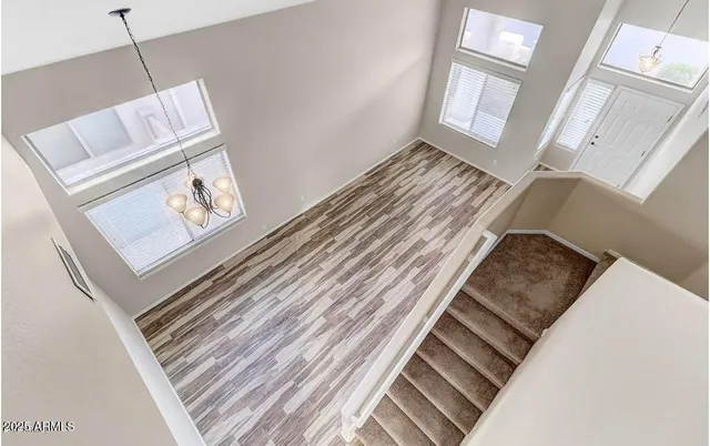 a view of an empty room with wooden floor and windows