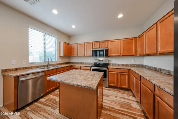 a kitchen with stainless steel appliances granite countertop wooden cabinets a sink and dishwasher a stove top oven with wooden floor