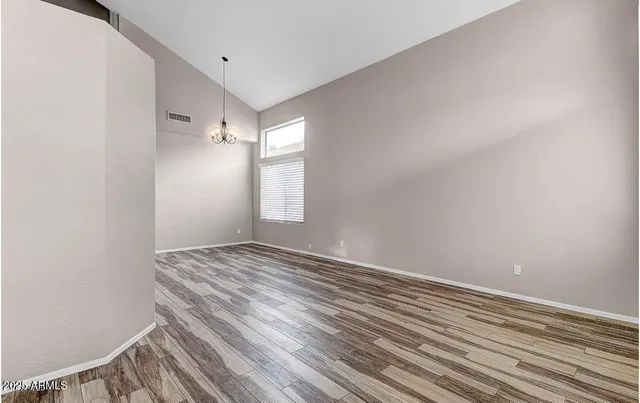 a view of empty room with window and wooden floor