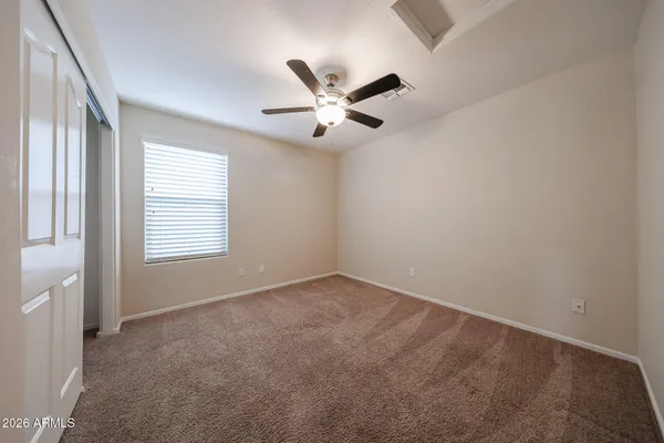 an empty room with a chandelier fan and wooden floor