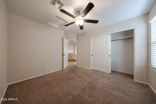 an empty room with a chandelier fan and windows