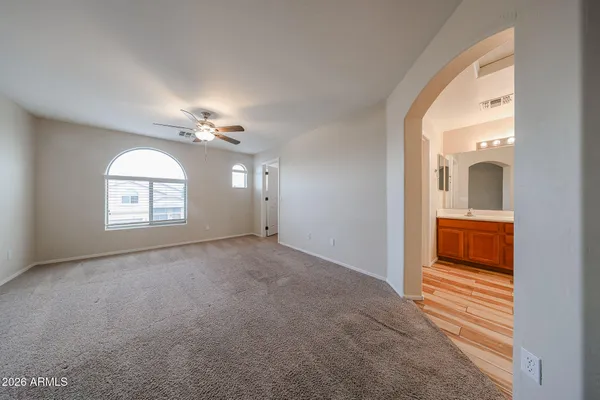 an empty room with chandelier fan and windows