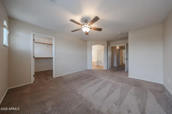 an empty room with a chandelier fan and window