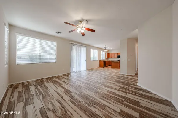 a view of empty room with wooden floor and fan