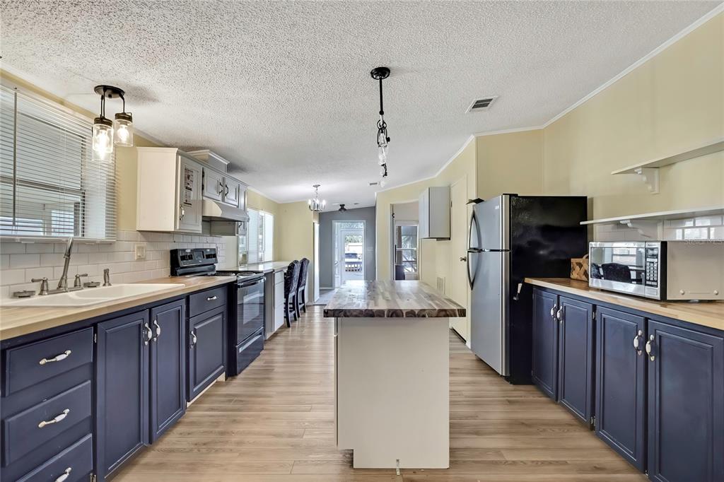 2400 Lemur Drive Holiday, FL 34690 - Photo 11 of 39 a large kitchen with stainless steel appliances kitchen island granite countertop a large counter top and wooden floors