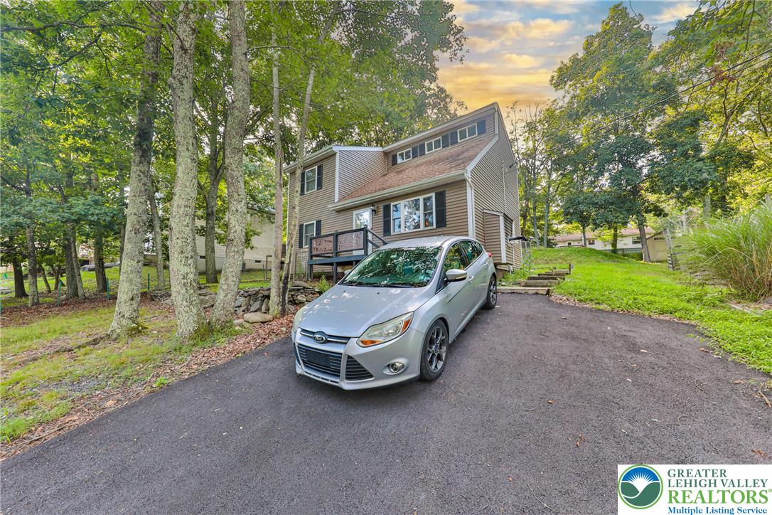 2114 Lakeview Road Bushkill, PA 18324 - Photo 65 of 83 Mature trees frame a multi-level home featuring classic siding and a paved driveway.