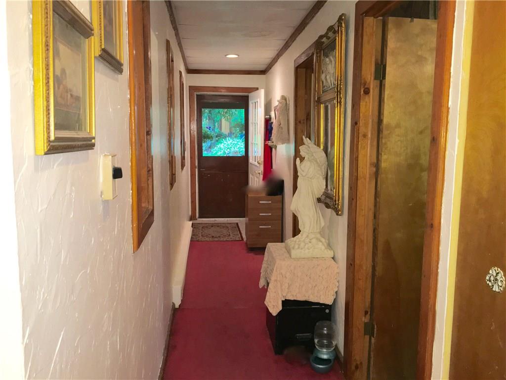 105 Plank Road Acme, PA 15610 - Photo 23 of 25 This hallway runs along side of the Dining Room and leads directly to the covered porch, yard, gold-fish pond and to the (4) car garage. The (2) Bedrooms are through the doors on the right.