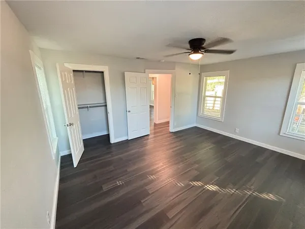 an empty room with wooden floor and windows