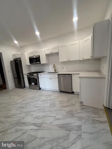 a view of kitchen with stainless steel appliances granite countertop a stove top oven a sink dishwasher and a refrigerator with wooden floor