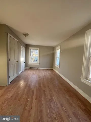 an empty room with wooden floor and window