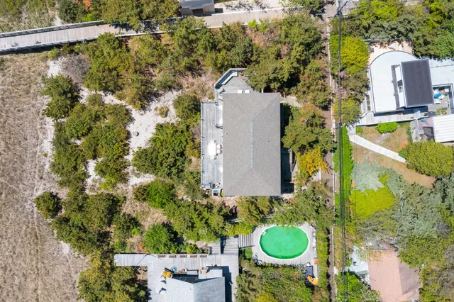 an aerial view of a house with swimming pool and large trees