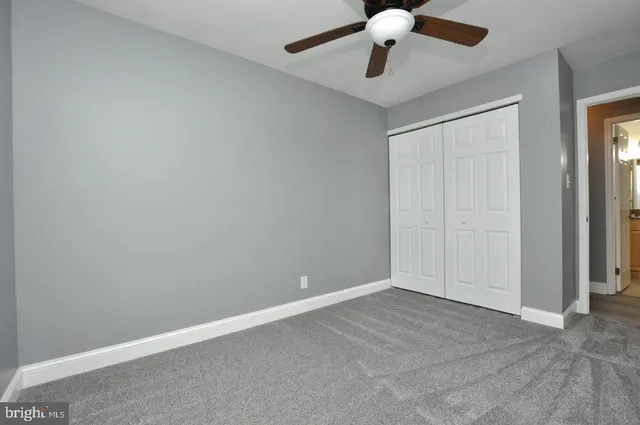 an empty room with a ceiling fan and carpet