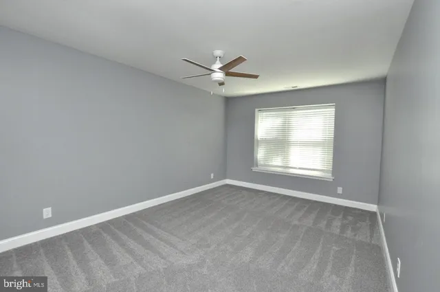 an empty room with a window and a ceiling fan