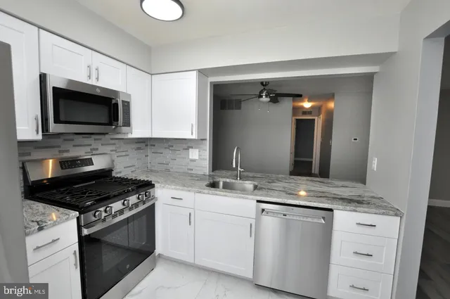 a kitchen with granite countertop a sink dishwasher stove and microwave with wooden floor