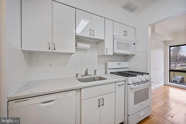 a kitchen with white cabinets and white appliances