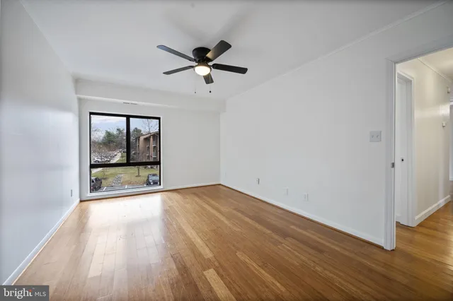 a view of an empty room with wooden floor and a window