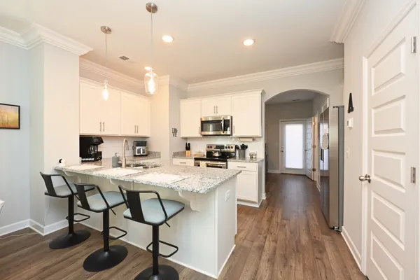 a kitchen with granite countertop a counter space chairs cabinets and stainless steel appliances