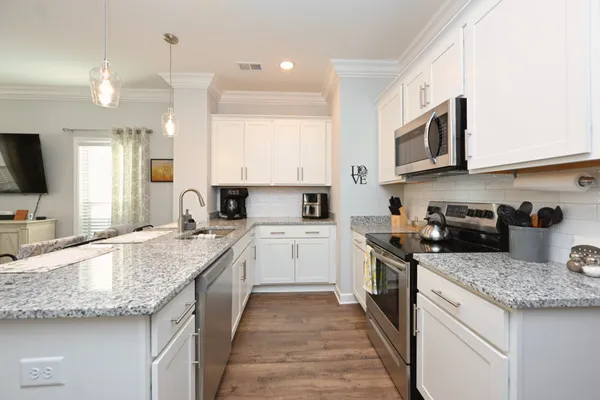 a kitchen with granite countertop a sink stainless steel appliances and white cabinets