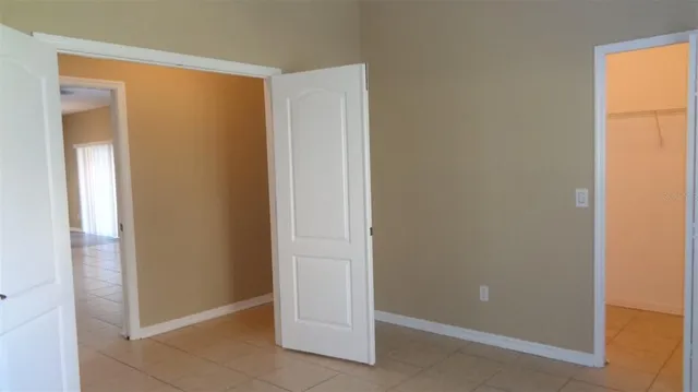 a view of a chandelier fan and window in an empty room