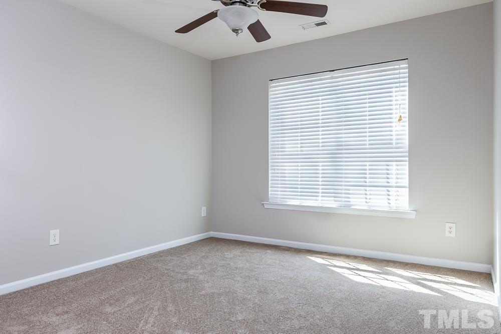 8722 Owl Roost Place Raleigh, NC 27617 - Photo 18 of 26 an empty room with a window and a fan