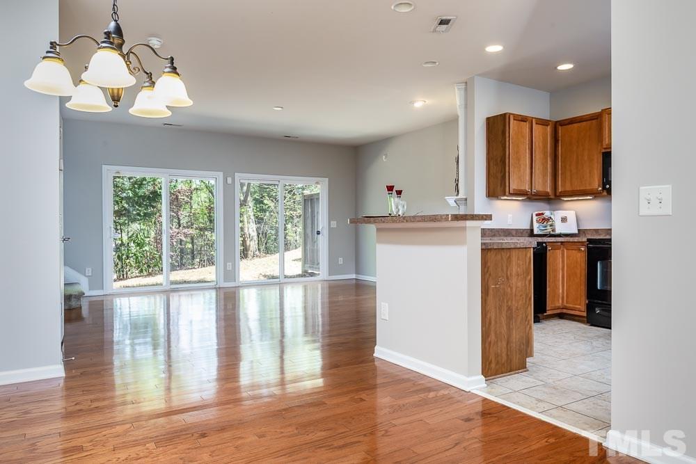 8722 Owl Roost Place Raleigh, NC 27617 - Photo 4 of 26 a kitchen with stainless steel appliances granite countertop a stove top oven a sink dishwasher and white cabinets with wooden floor