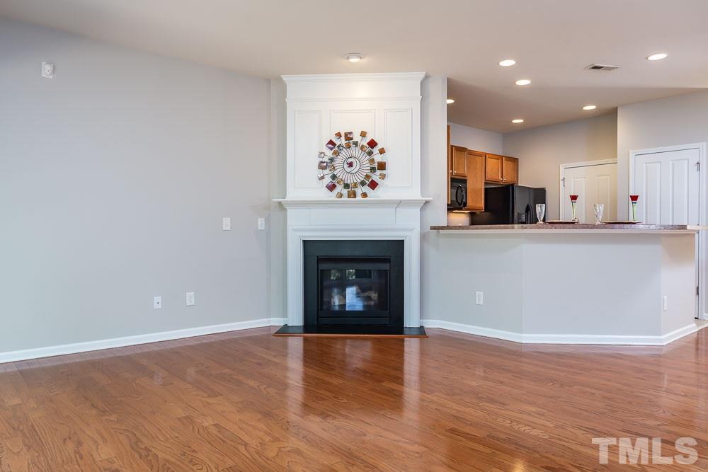 8722 Owl Roost Place Raleigh, NC 27617 - Photo 7 of 26 a view of a kitchen with a fireplace and wooden floor