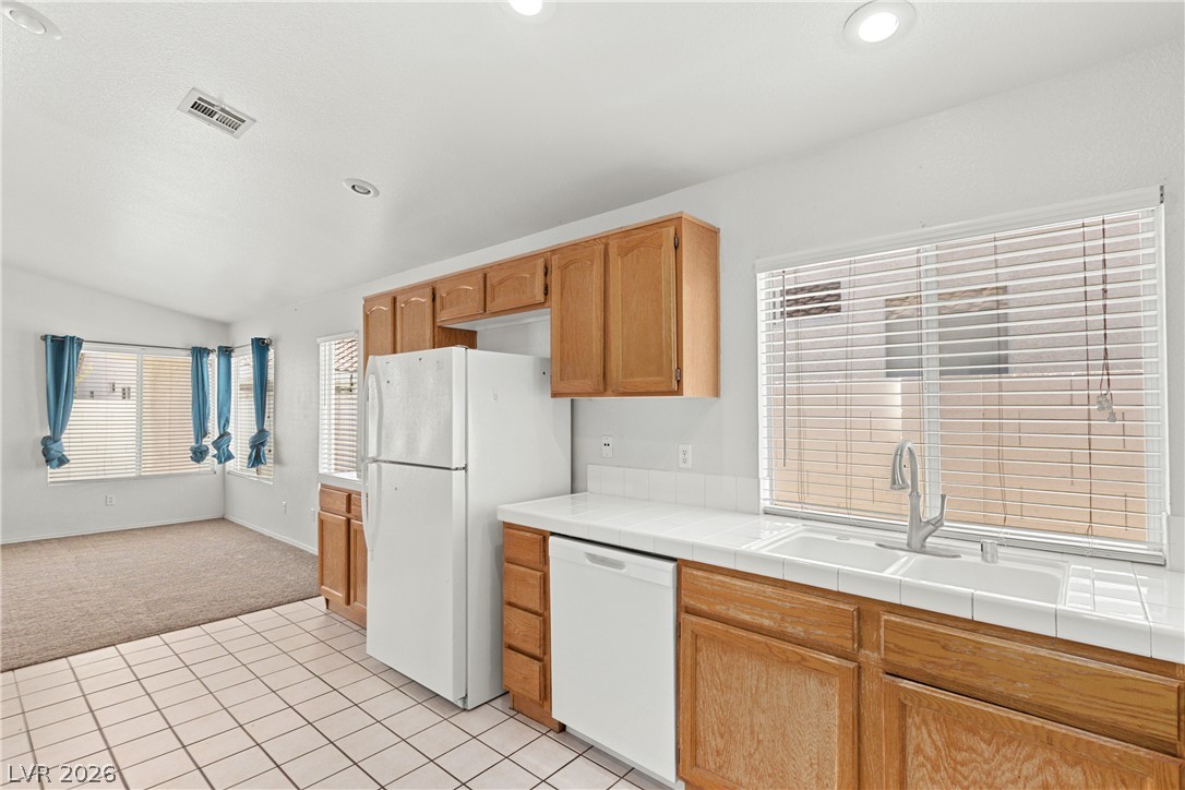 1815 Stablegate Avenue Henderson, NV 89012 - Photo 6 of 28 A well-lit kitchen with natural wood cabinetry and practical tile flooring awaits.