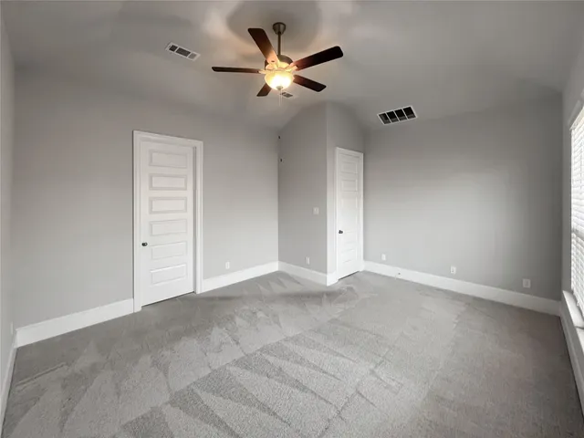 an empty room with closet and ceiling fan