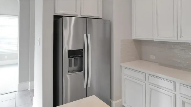 a kitchen with metallic refrigerator freezer and white cabinets