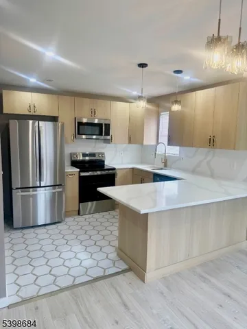 a kitchen with stainless steel appliances granite countertop a refrigerator a stove a sink and a microwave