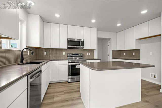 a kitchen with stainless steel appliances granite countertop a sink a stove a refrigerator a microwave and cabinets