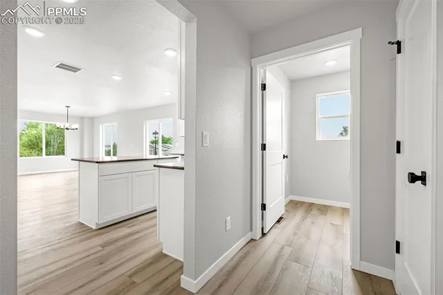 a view of a hallway with wooden floor and a kitchen