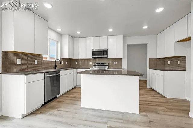 a kitchen with kitchen island granite countertop a stove top oven a sink a counter top space and cabinets