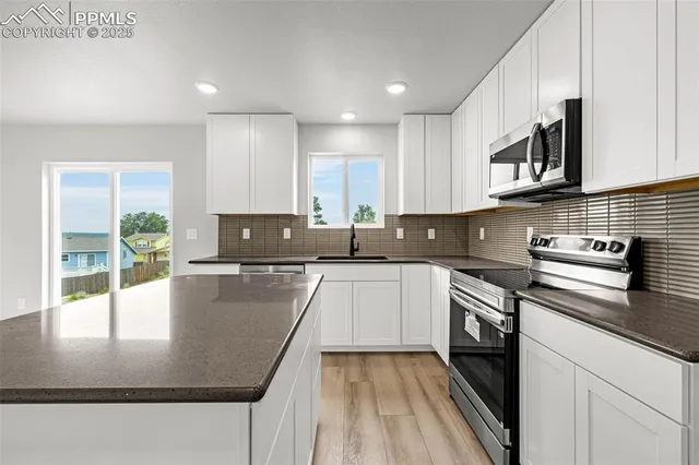a kitchen with stainless steel appliances granite countertop a sink a stove top oven a counter space and cabinets