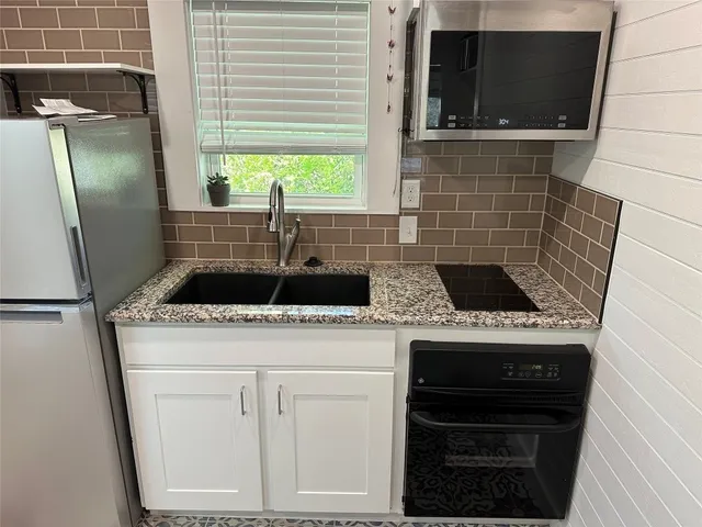 a kitchen with kitchen island a sink dishwasher a refrigerator and a stove with wooden floor