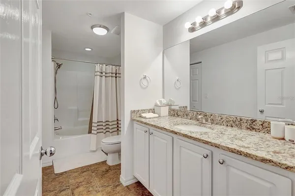 a bathroom with a granite countertop sink a toilet a shower and a mirror