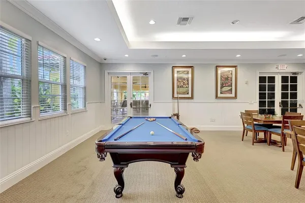 a living room with furniture pool table and windows