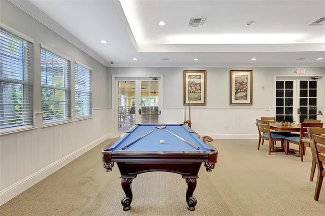 a living room with furniture pool table and windows