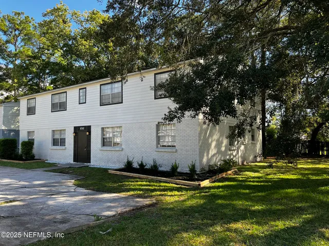 a view of a white house with a big yard and large trees