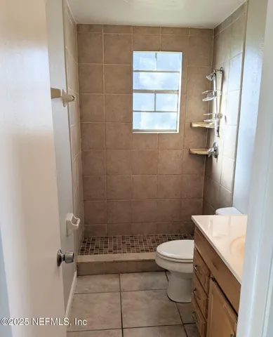 a bathroom with a granite countertop toilet a sink a shower and a window