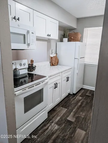 a kitchen with white cabinets and white appliances