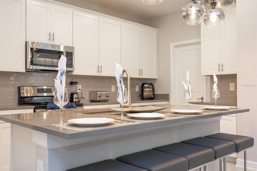 8964 Takeaway Way Davenport, FL 33896 - Photo 43 of 71 a kitchen with kitchen island granite countertop a sink cabinets and stainless steel appliances