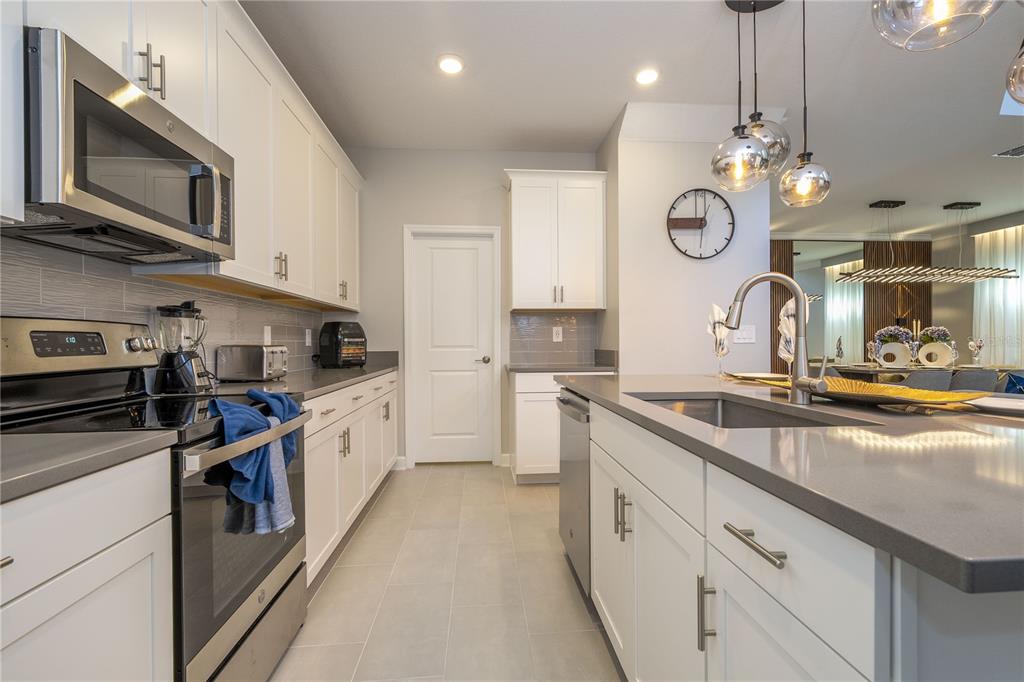 8964 Takeaway Way Davenport, FL 33896 - Photo 8 of 71 a large kitchen with stainless steel appliances granite countertop a stove a sink and a microwave