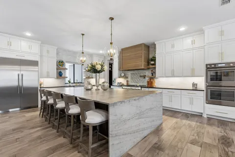 a large kitchen with kitchen island a island a sink a stove and chairs