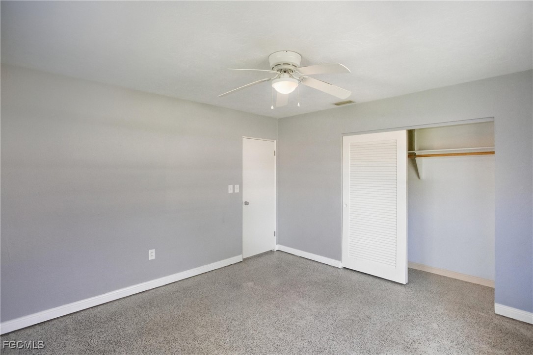 1440 Mandel Road Fort Myers, FL 33919 - Photo 13 of 40 an empty room with a chandelier fan and windows