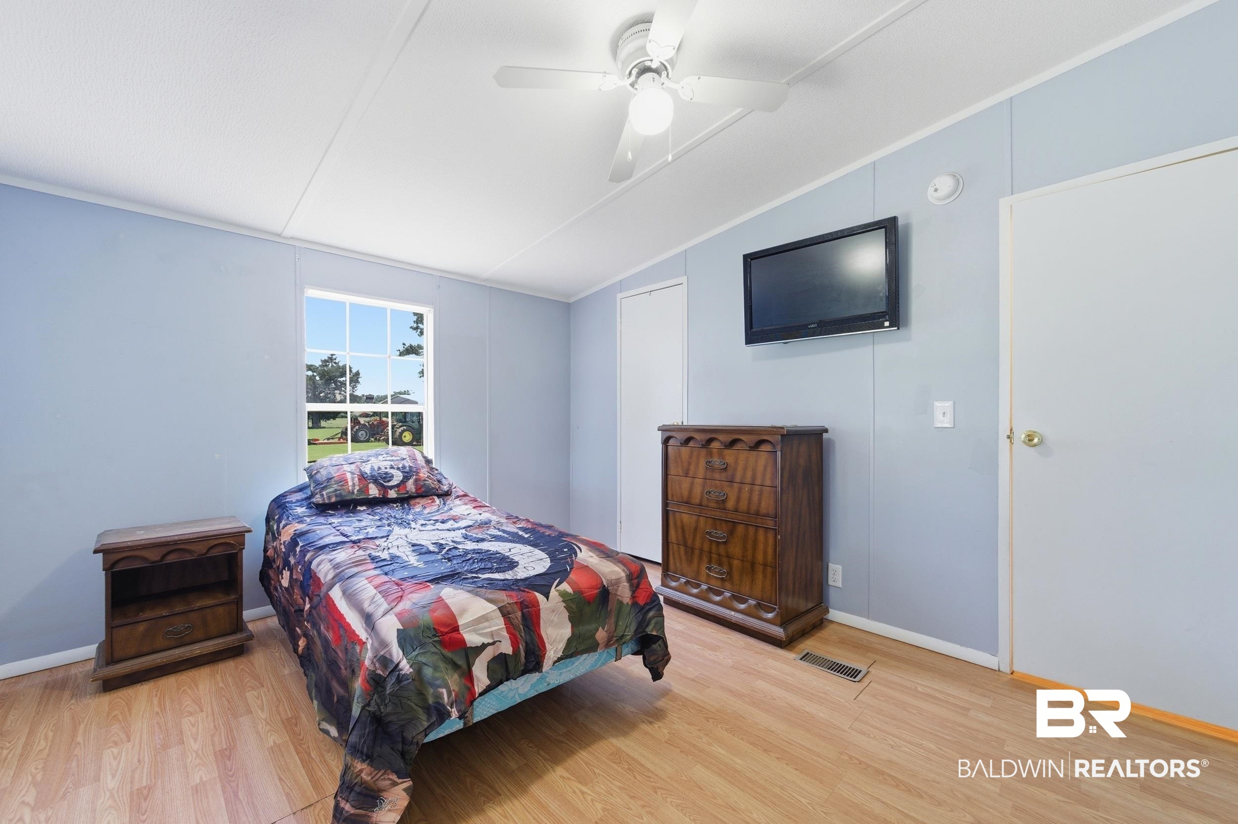 926 Tumbling Lane Atmore, AL 36502 - Photo 36 of 56 Room featuring wood-finish flooring, light blue panel walls, and a white ceiling with a ceiling fan