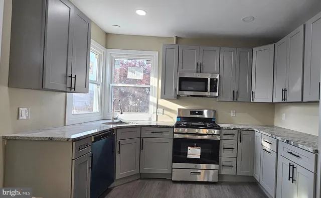 a kitchen with granite countertop a stove a sink and a microwave