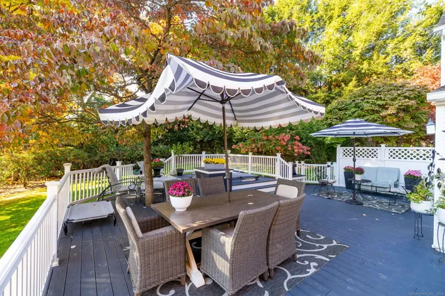 a view of a patio with a dining table and chairs under an umbrella with a barbeque grill and a small yard