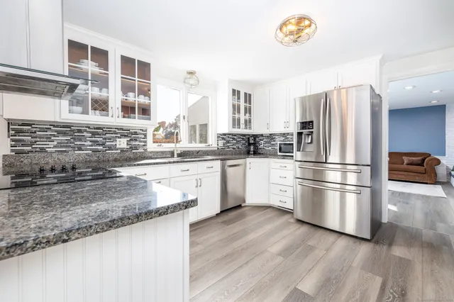 a kitchen with stainless steel appliances granite countertop a refrigerator a stove and a sink